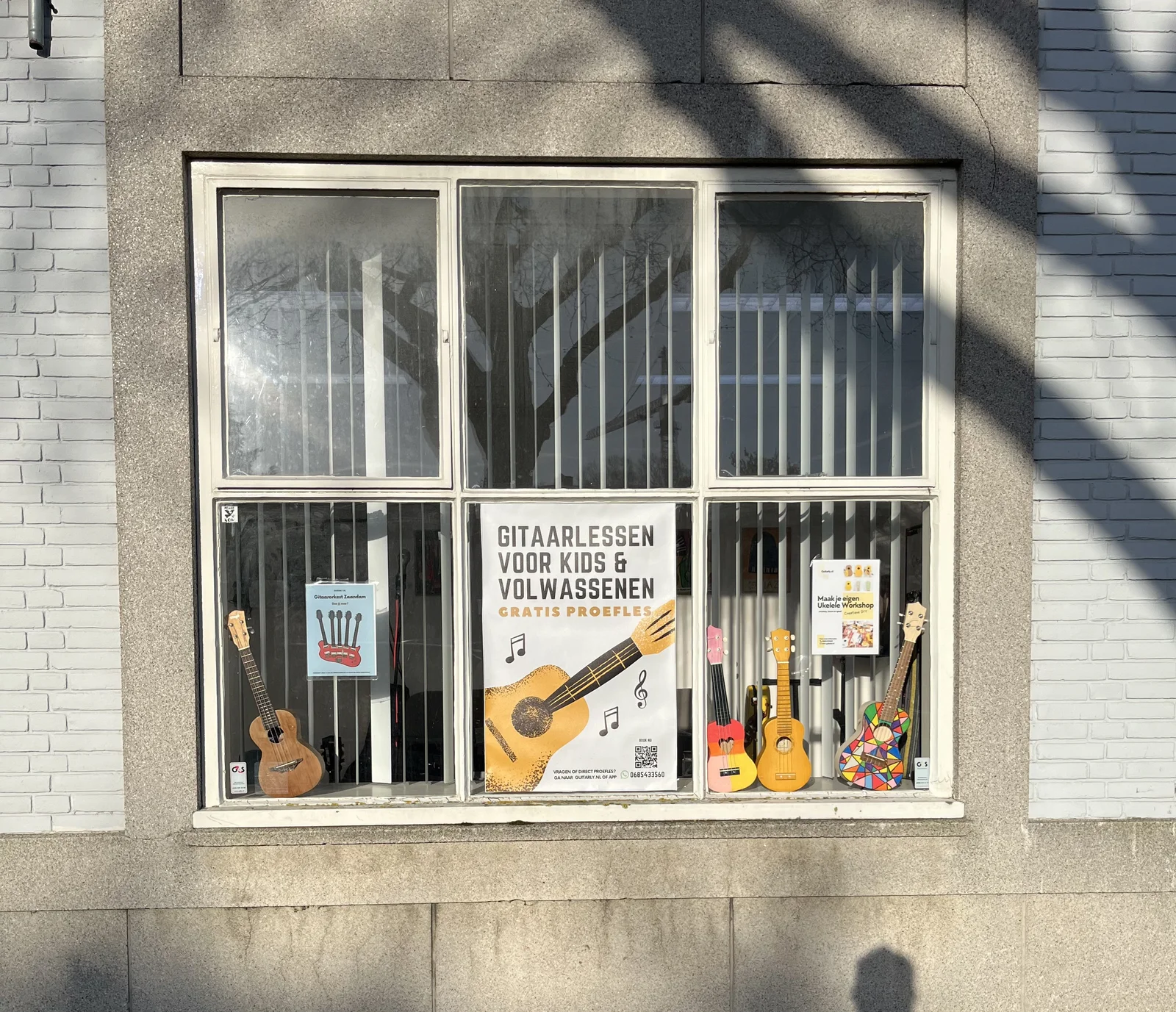 Etalage met ukeleles en posters voor gitaarlessen